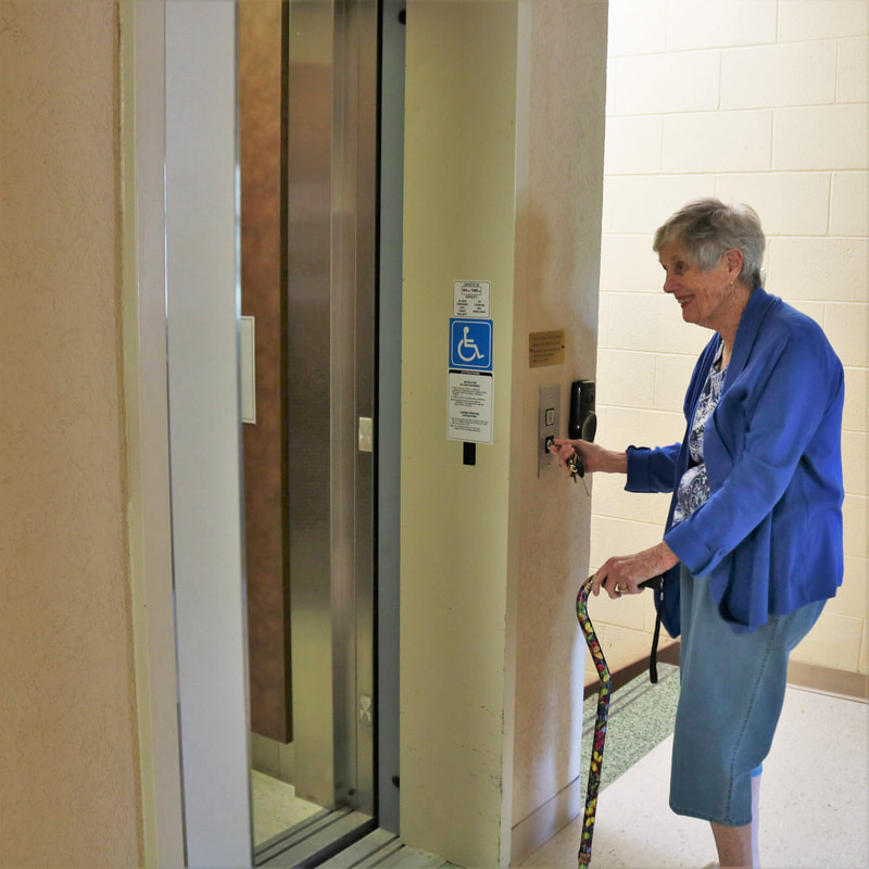 A photograph of a member of Harcourt about to enter the building's elevator by turning a key at its entrance.