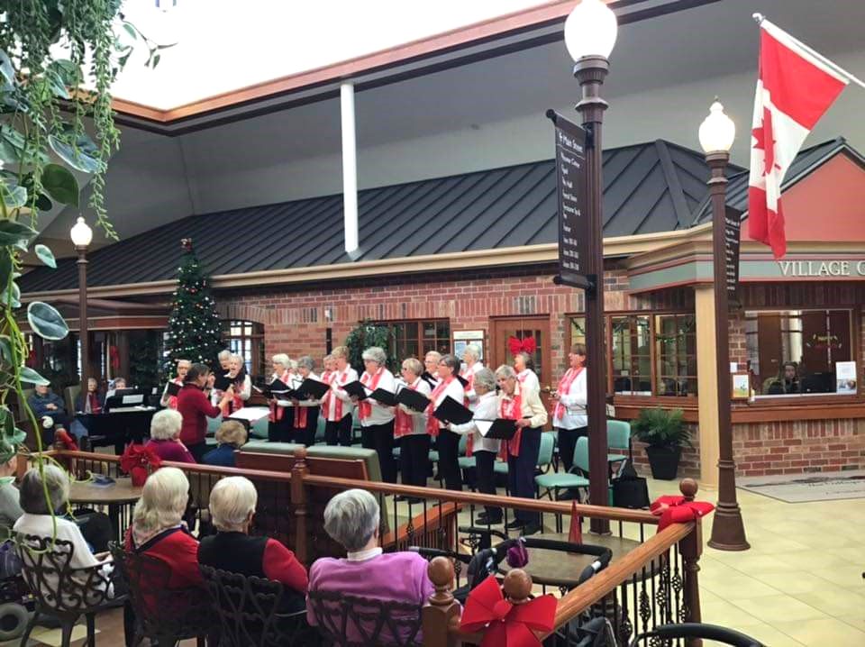 A photograph of the Lightshine singers performing for a crowd of seniors. There are about 15 singers.